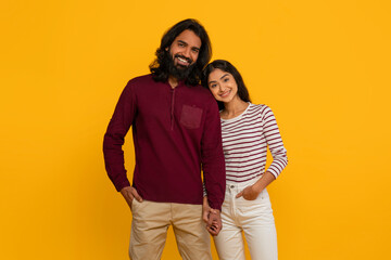 Happy young indian couple posing on yellow background