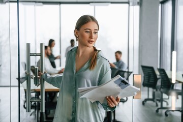 Female manager is with documents. Team of office workers are together indoors