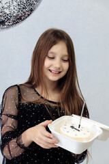 A little girl celebrates her 10th birthday. A girl on a white background in a black dress with long straight hair. Party, holiday