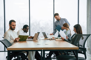 Bunch of laptops on the table. Team of office workers are together indoors