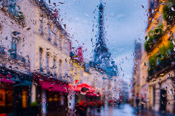 View through glass covered with raindrops to morning Paris in the fog, focus on raindrops