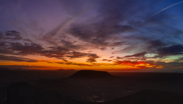Spectacular sun set image over Volcan Calderon Hondo volcanic crater silhouetted against the setting sun and skyscape near Corralejo, Fuerteventura, Canary Islands, Spain