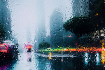 View through glass window with rain drops on blurred reflection silhouettesof a man andgirl in...