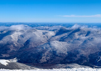 Fototapeta na wymiar The Wildcat and Carter Mountain Ranges in New Hampshire during the wintertime. These snowy 4000 footers are tall and cold on this clear NH wintertime.