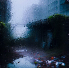 view through glass covered with raindrops onto the street of a small European town covered in morning fog. focus on raindrops