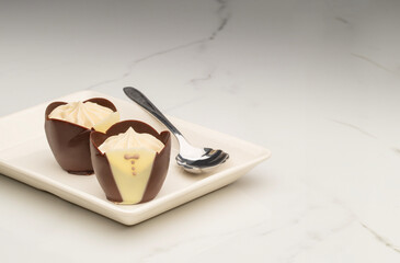 Two tuxedo dark chocolate mousse cups on a white plate