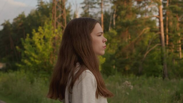 Woman stands near forest in evening