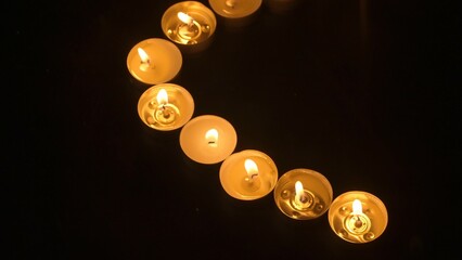 Rows of burning candles. The candles burn against a black backgrounds. The concept of a memorial...