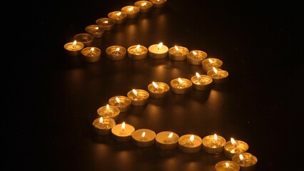Rows of burning candles. The candles burn against a black backgrounds. The concept of a memorial day. Background for advertising and design projects.