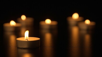 Burning candles. The candles burn against a black background and the flames move when the wind...