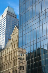 Two towering buildings, one made of glass, stand side by side in this urban landscape.