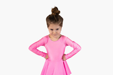 Portrait of an unhappy, angry and annoyed ballerina girl dressed in a pink dress and with her hair in a bun isolated on a white background, holding her hands in her arms, and looking with angry eyes