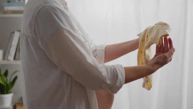 Looking forward to her baby, the expectant mother carefully collects a collection of children's clothing. A woman's hands easily flip through the diapers, creating an atmosphere of joy