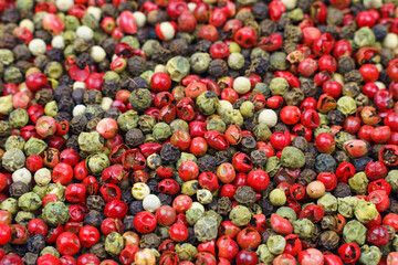 Top view of a mix of red, green, black, gray and white peppercorns.