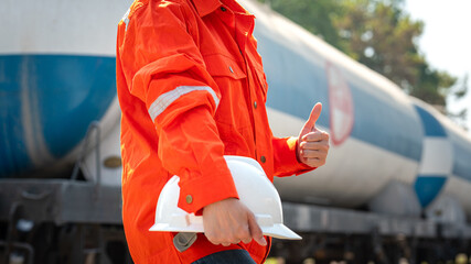 Action of a supervisor in orange coverall is thumbs up with holding a white safety helmet on the...