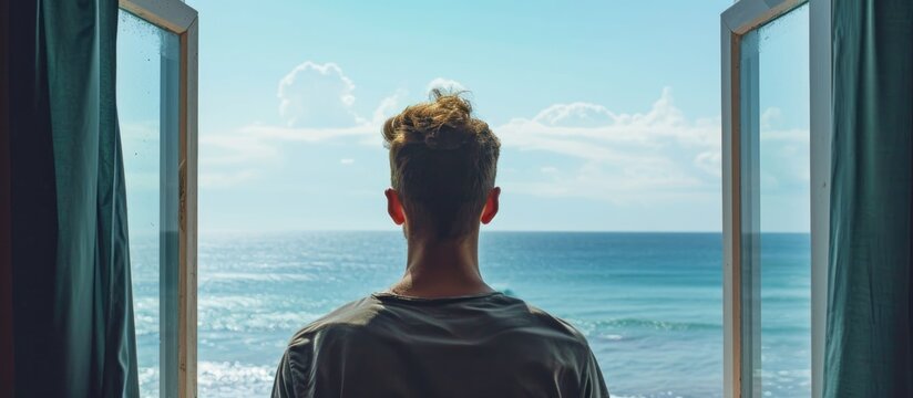 Male observing scenic ocean view from window