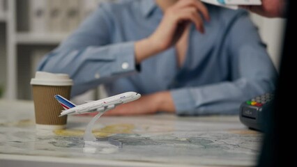 An experienced consultant with a mood issuing plane tickets in an authentic travel agency office space, in slow motion, a middle manager works to provide services to buyers preparing for summer travel