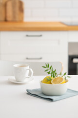 Fototapeta na wymiar A cup of tea with lemon and a teapot on a white table.