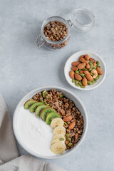 Healthy granola with yogurt, banana and kiwi in a bowl on a blue background.