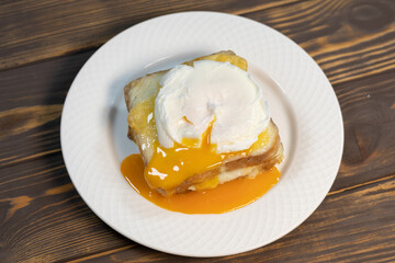 Croque madame, grilled sandwiches with sliced ham, melted cheese, dijon mustard and poached egg on  bechamel sauce.