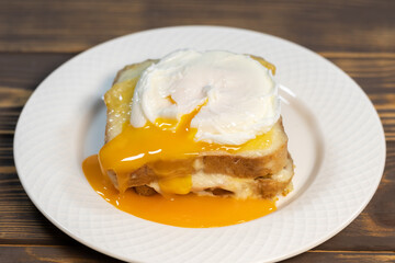 Croque madame, grilled sandwiches with sliced ham, melted cheese, dijon mustard and poached egg on  bechamel sauce.