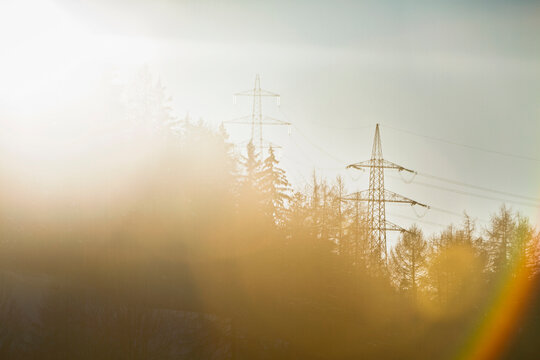 Power lines on mountain side with lens flares.