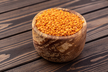 Photo of red lentils in wooden bowl with wooden measuring cup on wooden background.  Healthy lifestyle. Vegetarian and vegan diet.