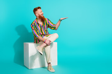 Full body length photo of red hair macho hipster sit podium holding arm new perfume advertisement isolated on cyan color background