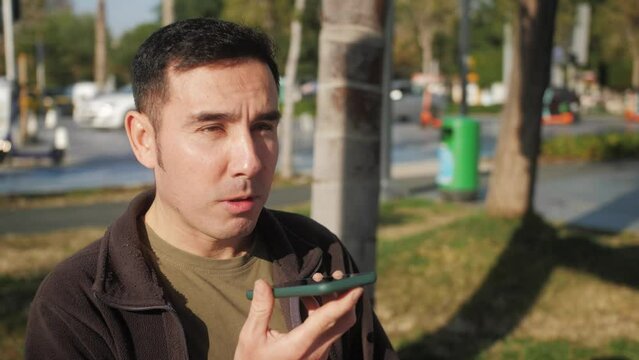 Arab millennial businessman talk on speakerphone with friend makes voice recognition use virtual assistant digital application record audio message on mobile app.