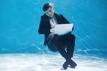 Fototapeta premium Business man working using laptop while underwater