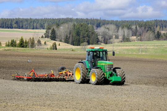 Working in field with John Deere 7710 tractor and Potila Magnum 800 Plus seedbed cultivator on a day of spring. 