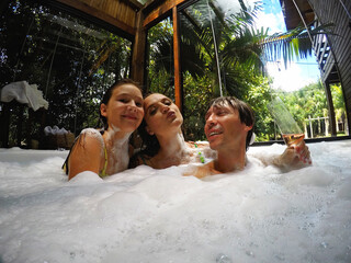 familia feliz em spa relaxante, jacuzzi com espumas 