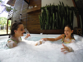 mãe e filha juntas felizes brincando em banheira de espumas em spa de luxo 
