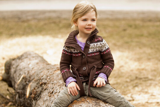 Young girl climbing on tree stump at the playground. Munich, Germany