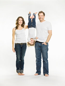Studio shot of family, mother, daughter and father all wearing white t-shirts and jeans, cut out. Munich, Germany