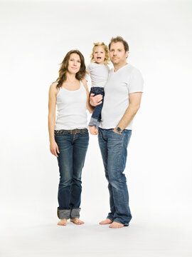 Studio shot of family, mother, daughter and father all wearing white t-shirts and jeans, cut out. Munich, Germany