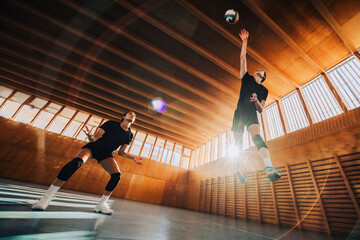 Low angle view of a volleyball players in action hitting a ball.