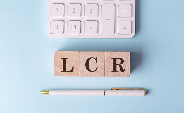 LCR on wooden cubes with pen and calculator, financial concept