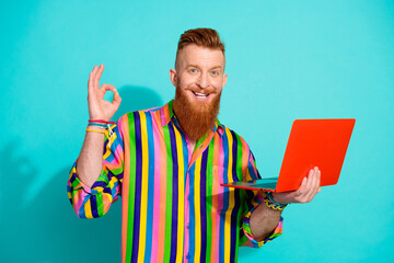 Photo of experienced it gamedev expert show okey sign on freelance market holding his light laptop isolated over blue color background