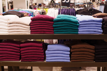 Pile of different colors of t-shirts on shelves in a store 