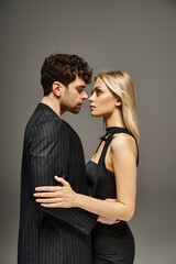 side view of beautiful young couple kissing on grey background, man and woman in love concept