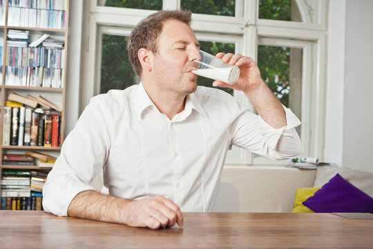 Man drinking milk at the dinner table. Munich, Germany