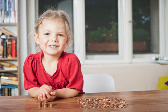 Young girl counting pennies on the table.