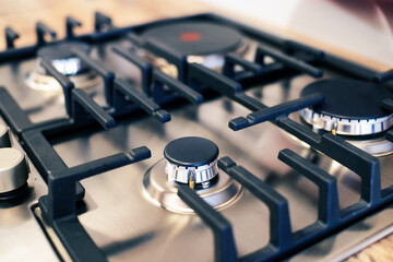 Modern new gas built-in stainless steel hob with burners close-up, gas stove, soft focus. Household...