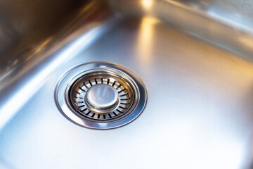 Close-up of a modern new stainless steel kitchen sink with a filter plug on the drain hole. Kitchen...