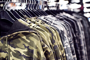 Outerwear, row of military-colored hoodies on hangers in a clothing store close-up, soft selective...