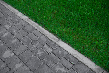 Abstract background with sidewalk and green grass. Summer  sun  footpath garden paving stones landscape country texture track pedestrian path green grass grows near tiles diagonal line