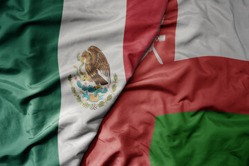 big waving national colorful flag of oman and national flag of mexico .