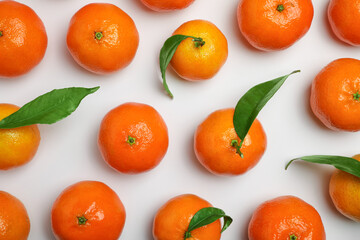 Delicious tangerines and green leaves on white background, flat lay