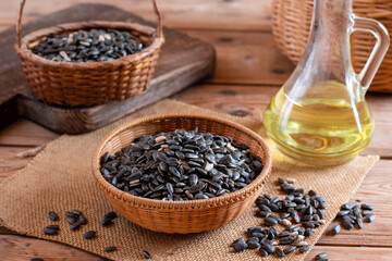 Pile of black sunflower seeds on wooden elm slab, selective focus